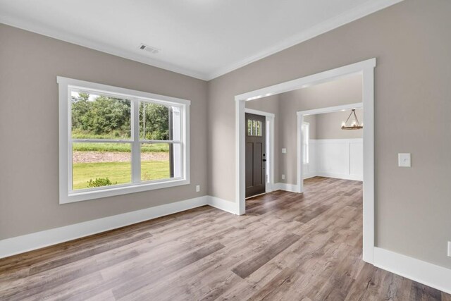 unfurnished room featuring hardwood / wood-style flooring, crown molding, and a chandelier