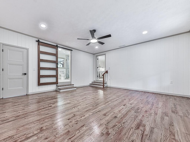 221 Wonewok Dr, Canton, GA 30114 - unfurnished living room featuring wood finished floors, a ceiling fan, a barn door, ornamental molding, and recessed lighting