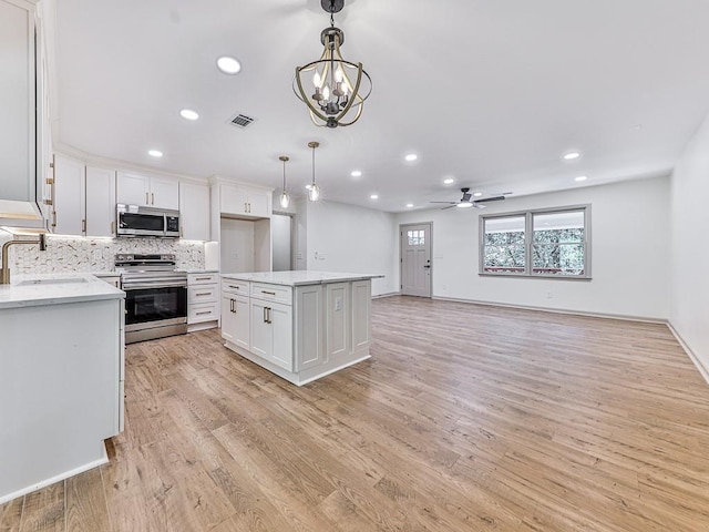 221 Wonewok Dr, Canton, GA 30114 - kitchen with appliances with stainless steel finishes, light wood-style flooring, white cabinetry, ceiling fan, and a chandelier