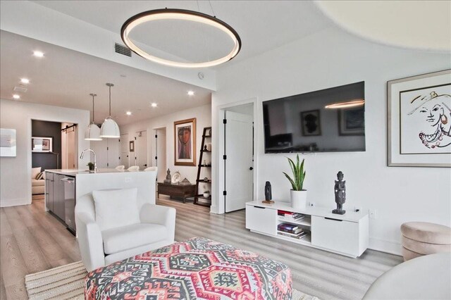 kitchen featuring a breakfast bar, sink, pendant lighting, stainless steel appliances, and a barn door