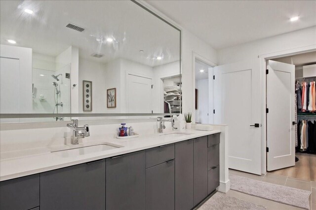 kitchen featuring wall chimney exhaust hood, high end appliances, white cabinetry, decorative light fixtures, and a center island with sink