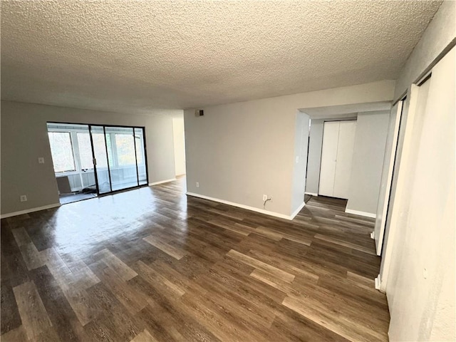 empty room with dark hardwood / wood-style flooring and a textured ceiling