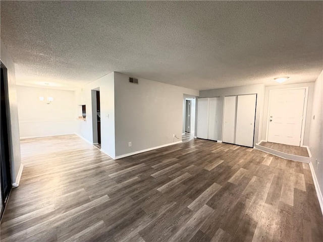 unfurnished room featuring a notable chandelier, dark hardwood / wood-style flooring, and a textured ceiling