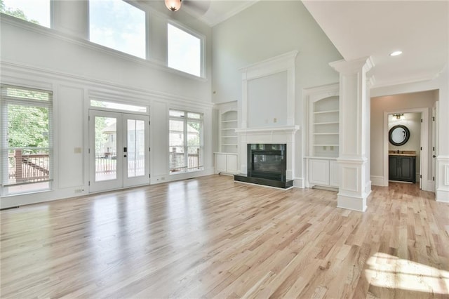 5121 Hope Ct SW, Lilburn, GA 30047 - unfurnished living room featuring a towering ceiling, light wood-type flooring, a high end fireplace, crown molding, and built in features