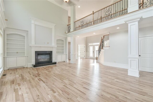 5121 Hope Ct SW, Lilburn, GA 30047 - unfurnished living room featuring decorative columns, a high ceiling, light wood-type flooring, built in features, and ornamental molding