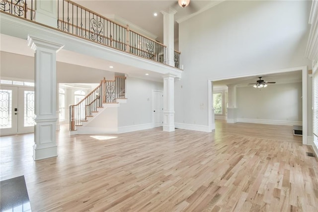 5121 Hope Ct SW, Lilburn, GA 30047 - unfurnished living room with decorative columns, a ceiling fan, stairway, a high ceiling, and light wood-style flooring