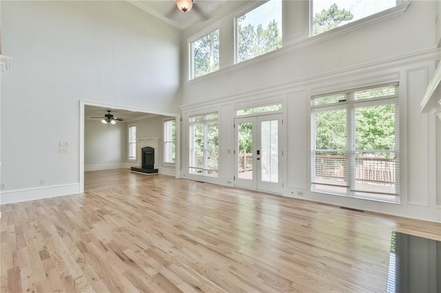 5121 Hope Ct SW, Lilburn, GA 30047 - unfurnished living room with a fireplace with raised hearth, a high ceiling, a ceiling fan, crown molding, and light wood-style flooring