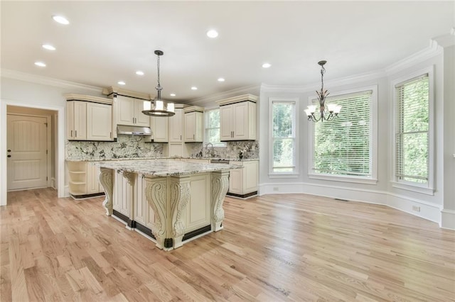 5121 Hope Ct SW, Lilburn, GA 30047 - kitchen featuring under cabinet range hood, a chandelier, ornamental molding, decorative backsplash, and light wood-style floors