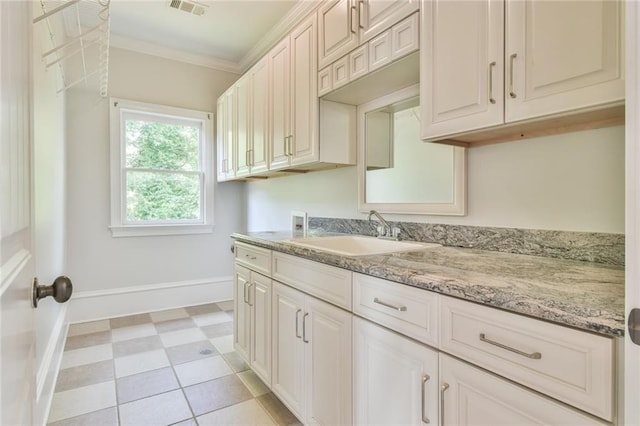 5121 Hope Ct SW, Lilburn, GA 30047 - kitchen featuring a sink, baseboards, crown molding, light stone counters, and light flooring