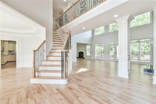 5121 Hope Ct SW, Lilburn, GA 30047 - stairs with a high ceiling, decorative columns, ornamental molding, wood finished floors, and a decorative wall