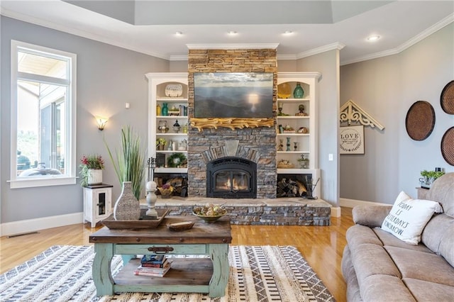 living room featuring a stone fireplace, crown molding, and light wood-type flooring