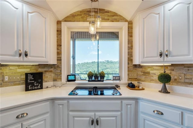 kitchen featuring decorative backsplash, white cabinetry, vaulted ceiling, and black electric stovetop