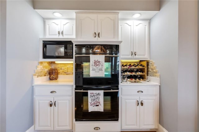 kitchen featuring tasteful backsplash, black appliances, and white cabinets