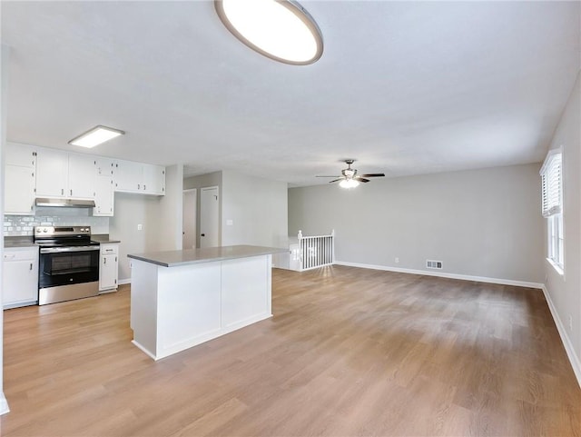 kitchen featuring backsplash, stainless steel electric range, white cabinets, and light wood-type flooring