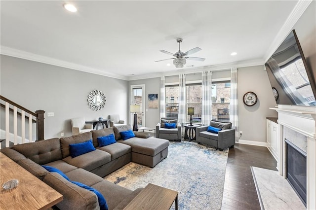 living area featuring ornamental molding, plenty of natural light, a fireplace, and stairway