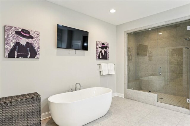 bathroom with a stall shower, baseboards, a freestanding tub, and tile patterned floors