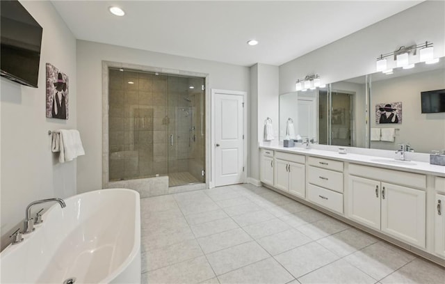 full bath featuring double vanity, tile patterned flooring, a freestanding bath, a shower stall, and a sink