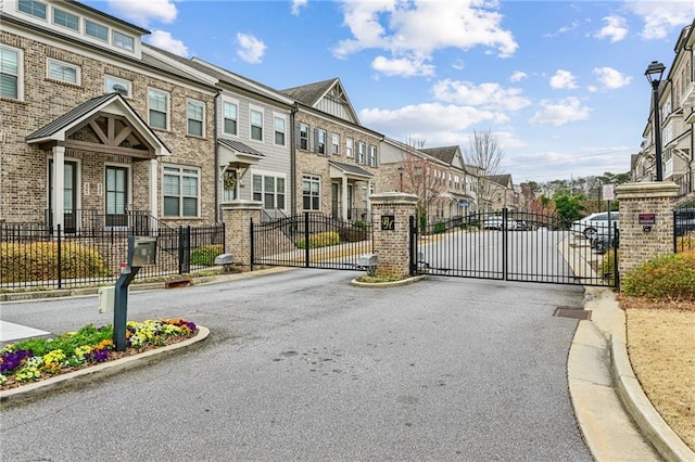 view of street featuring a gate, a residential view, a gated entry, and curbs