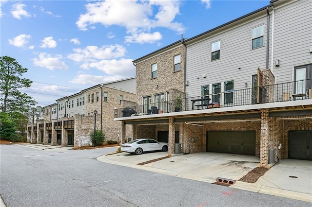 view of property with a garage, driveway, and central AC unit