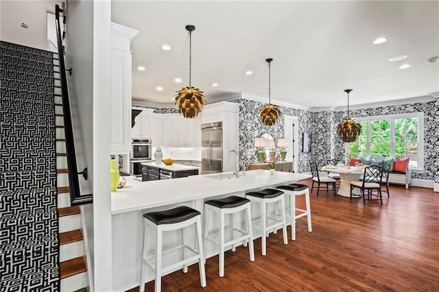 kitchen with sink, a breakfast bar area, white cabinetry, hanging light fixtures, and stainless steel appliances