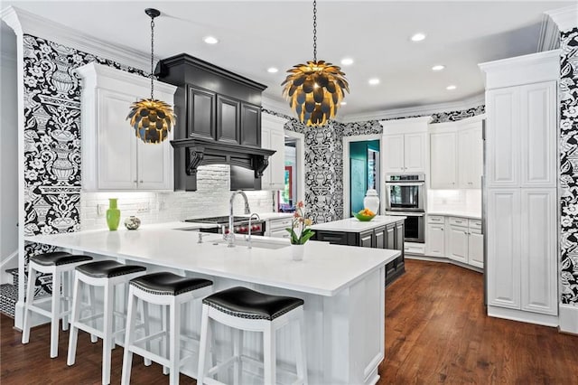 kitchen with white cabinetry, hanging light fixtures, kitchen peninsula, stainless steel appliances, and crown molding