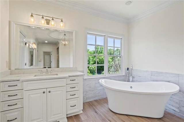 bathroom with a bathing tub, hardwood / wood-style floors, tile walls, ornamental molding, and vanity