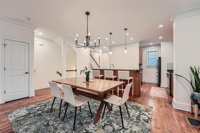 dining area featuring ornamental molding, a chandelier, and hardwood / wood-style floors