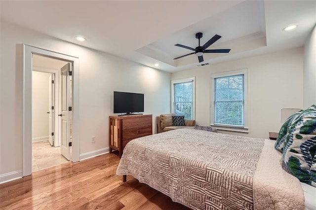 bedroom featuring ceiling fan, a raised ceiling, and light hardwood / wood-style flooring