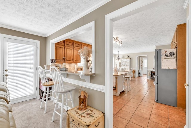 3574 Timberloch Trl, Snellville, GA 30039 - kitchen featuring freestanding refrigerator, a textured ceiling, healthy amount of natural light, a kitchen breakfast bar, and brown cabinets