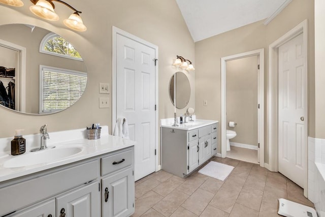 3574 Timberloch Trl, Snellville, GA 30039 - full bath featuring two vanities, vaulted ceiling, toilet, a tub, and tile patterned flooring