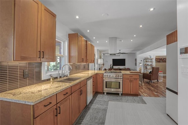 kitchen with light stone counters, a peninsula, a sink, stainless steel appliances, and open floor plan