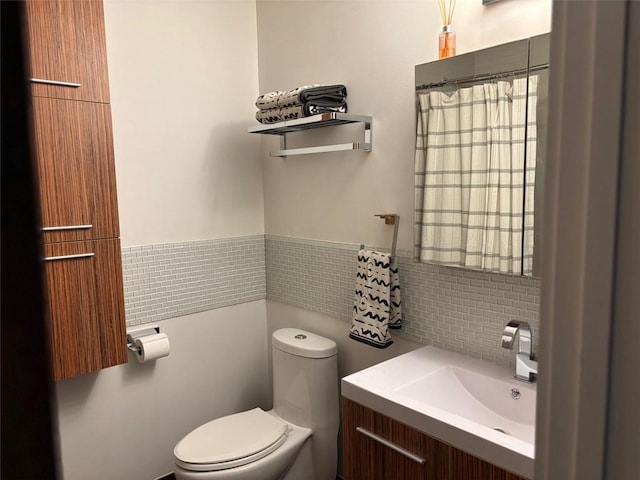 bathroom featuring vanity, tile walls, and toilet