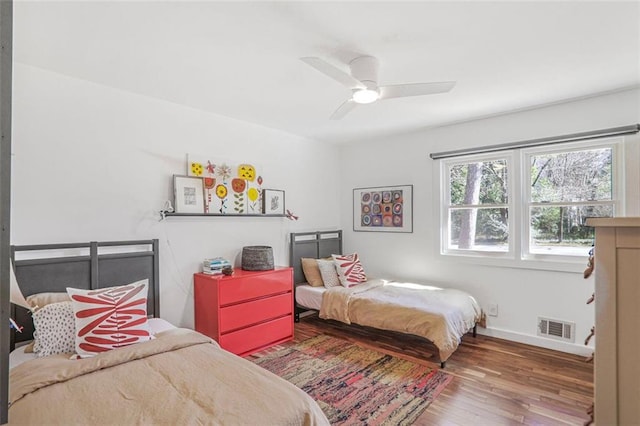 bedroom with visible vents, baseboards, wood finished floors, and a ceiling fan