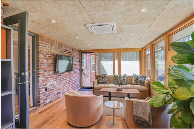 living area featuring recessed lighting, wood finished floors, visible vents, and brick wall