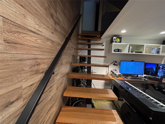 stairway featuring wood walls