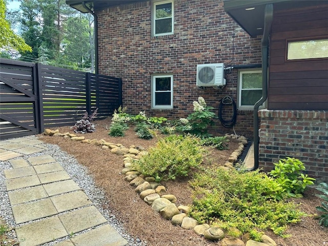 view of property exterior featuring ac unit, brick siding, and fence