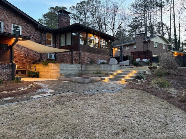 rear view of property featuring a patio, brick siding, and a chimney