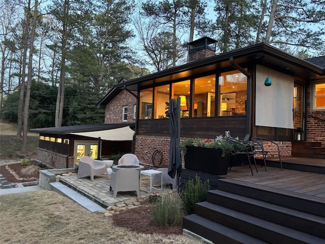 rear view of house featuring a patio area, french doors, brick siding, and a chimney