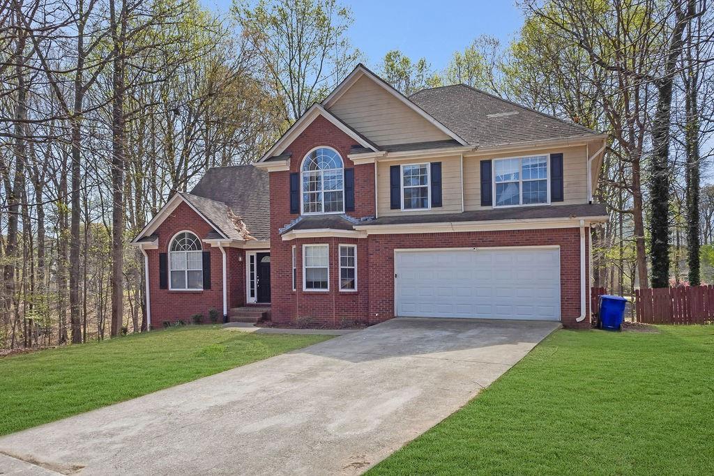 view of front of house featuring driveway, brick siding, and an attached garage