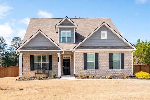 craftsman-style home featuring fence and brick siding