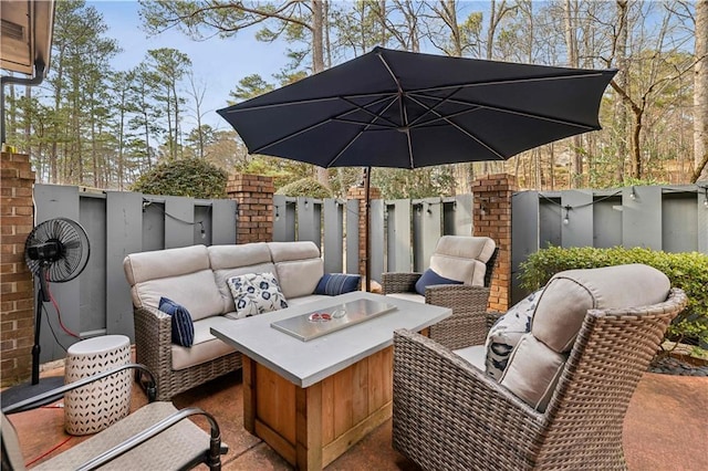 view of patio with an outdoor living space with a fire pit and fence