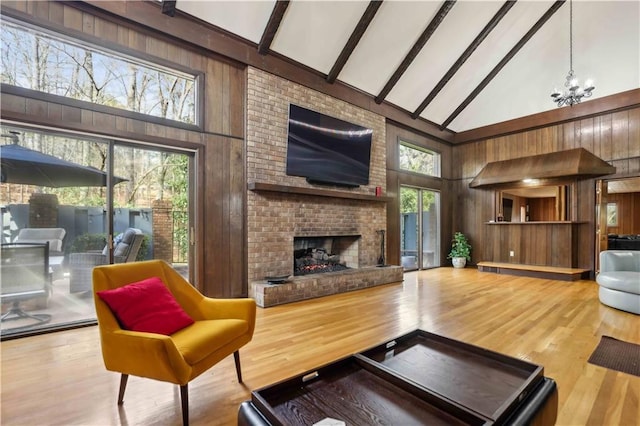 living area featuring high vaulted ceiling, wood walls, and a brick fireplace