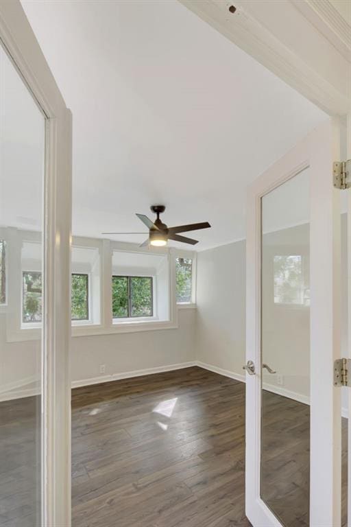 empty room featuring ceiling fan, wood finished floors, and baseboards