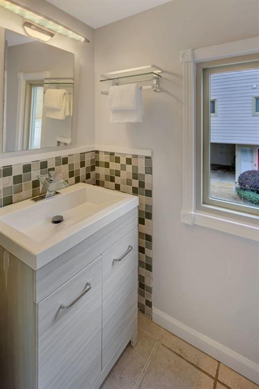 bathroom featuring vanity, baseboards, tile walls, and tile patterned floors