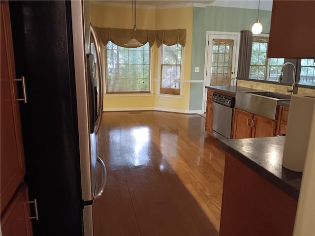 kitchen featuring pendant lighting, hardwood / wood-style floors, sink, ornamental molding, and appliances with stainless steel finishes