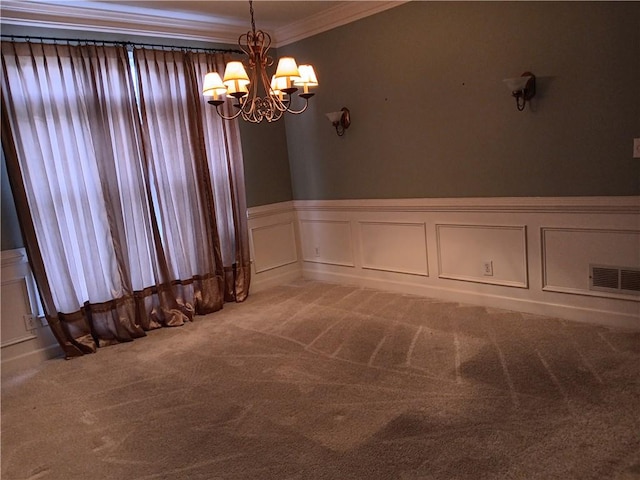 spare room featuring carpet floors, crown molding, and a chandelier