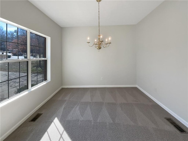 carpeted spare room featuring baseboards, visible vents, and a chandelier