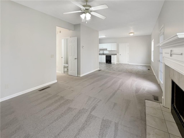 unfurnished living room featuring visible vents, a fireplace with flush hearth, a sink, baseboards, and light colored carpet