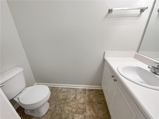 half bath with vanity, toilet, and baseboards