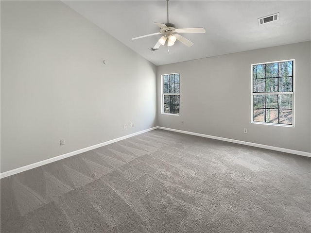 carpeted empty room featuring lofted ceiling, baseboards, visible vents, and ceiling fan